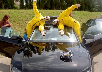 Walk Act Künstler als Crashtest Dummies bei einem Outdoor Auto Event auf einem Auto
