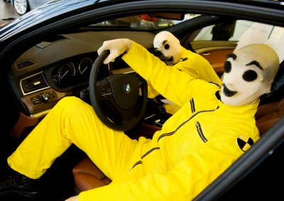 Walk Act Künstler als Crashtest Dummies bei einem Auto Event im Autohaus, in einem Auto sitzend